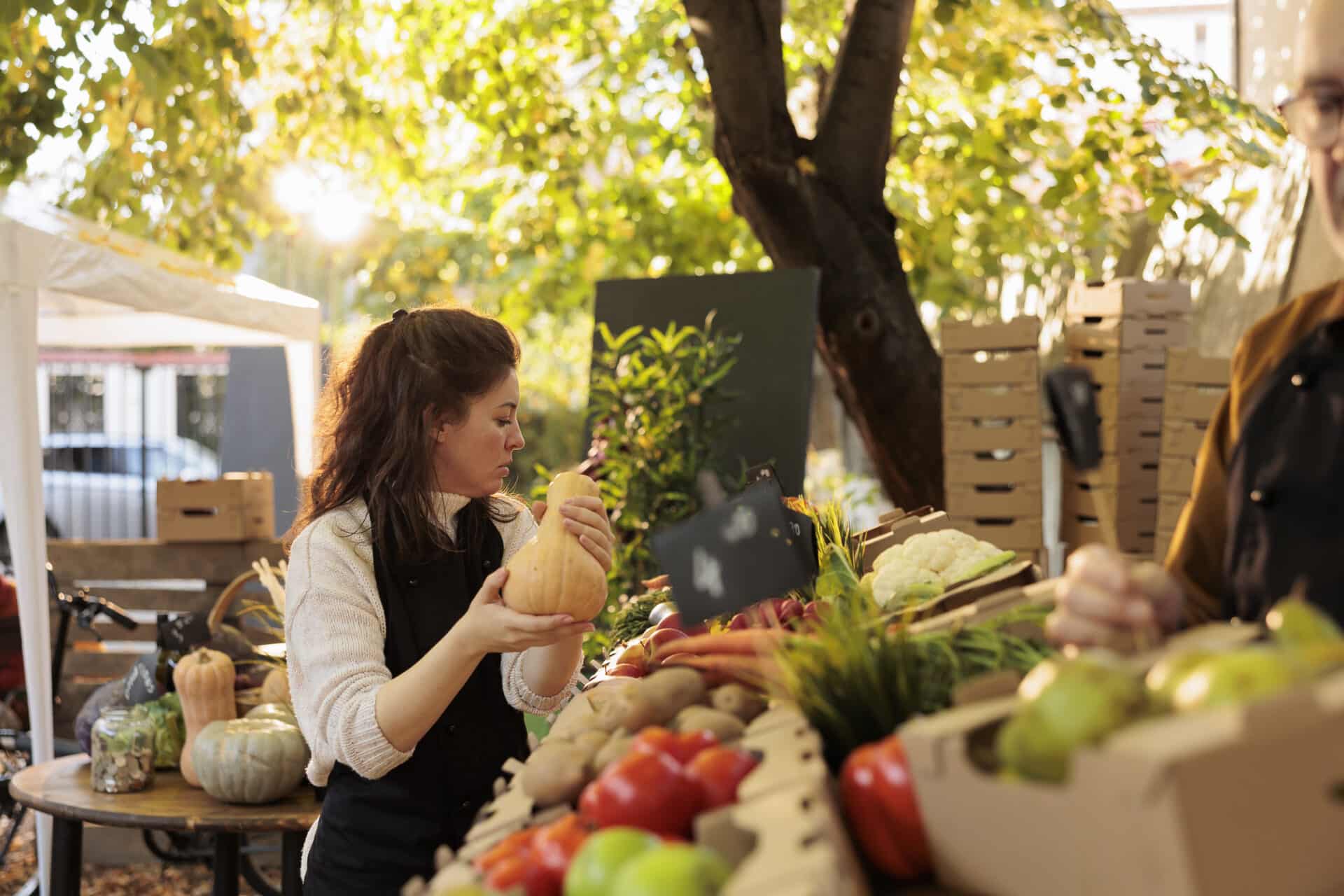 Young vendor arranging fresh natural products at farmers market stall