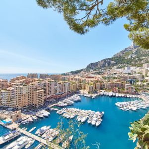Panoramic image of Port Fontvieille - Monaco, top view from Monaco Ville, azur water, sun reflections on the water, harbour at sunny day, luxury apartments, a lot of yachts and boats, mountain. High quality photo