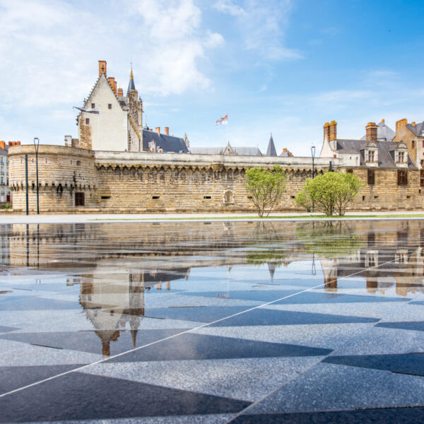 View on the castle of Dukes of Brittany with water mirror fountain in Nantes city in France